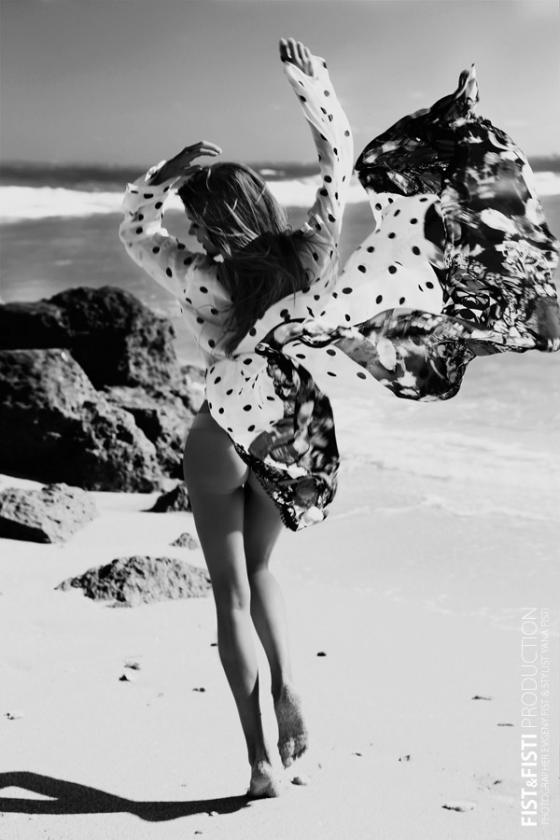 Черно-белая фотография двеушка бежит по пляжу