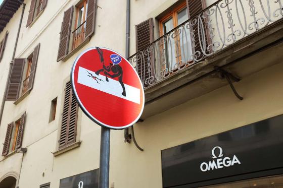 Стрит-арт человечек ломает знак стоп в городе Флоренция в Италии